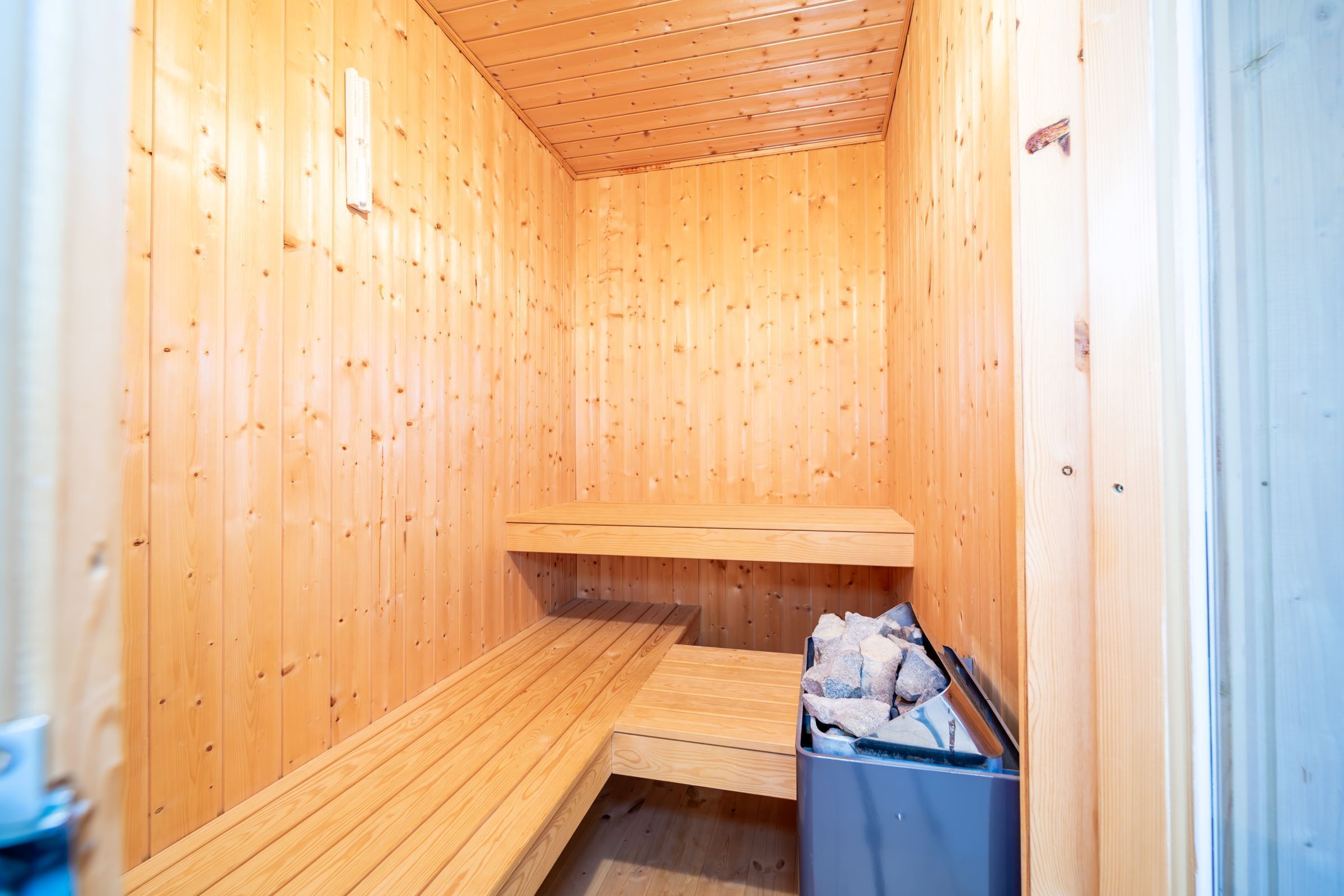 Un sauna en bois avec un banc et une poubelle.