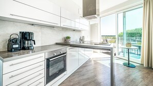 A modern kitchen with white cabinets, a built-in oven, and a coffee maker. - Promenade Villa 03 Apartment 11 (Lübeck-Travemünde)