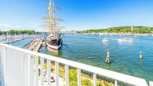 A harbor with a tall ship docked, surrounded by smaller boats and a marina. - Promenade Villa 03 Apartment 11 (Lübeck-Travemünde)