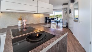 Een moderne keuken met een zwart inductiefornuis, witte kasten en een marmeren aanrecht.
