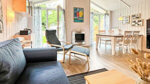 A modern living room with a sofa, armchairs, a dining table, and a fireplace. - Vacation home Schatzkiste 18 (Lübeck-Travemünde)