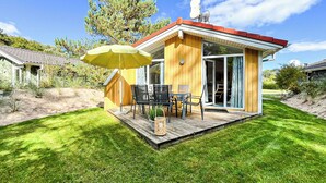 A wooden cabin with a deck, outdoor furniture, and a satellite dish. - Vacation home Schatzkiste 18 (Lübeck-Travemünde)