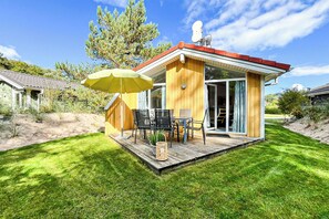 Eine Holzhütte mit einer Terrasse, Gartenmöbeln und einer Satellitenschüssel.