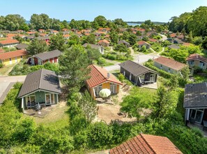 Een woonwijk met meerdere huizen, sommige met een garage, omgeven door groen en een heldere lucht.