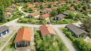 A residential area with houses featuring red-tiled roofs, surrounded by greenery and a clear view of the sea. - Vacation home Schatzkiste 18 (Lübeck-Travemünde)