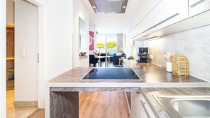 Una cocina moderna con una isla central, estufa integrada y un amplio ventanal con vistas a zonas verdes.