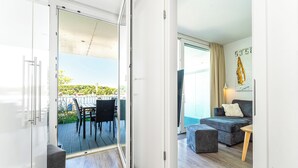 Un salón moderno con un sofá gris, una mesa de centro de madera y un balcón con zona de comedor.