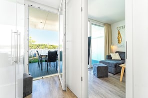 A modern living room with a grey sofa, a wooden coffee table, and a balcony with a dining area. - Promenade Villa 03 Apartment 02 (Lübeck-Travemünde)