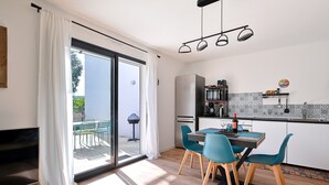 Eine moderne Küche mit Essbereich, einem Fernseher und einer Glasschiebetür, die auf eine Terrasse im Freien führt.