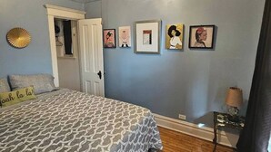 Un dormitorio con cama, ventilador de techo, puerta y decoración en la pared.