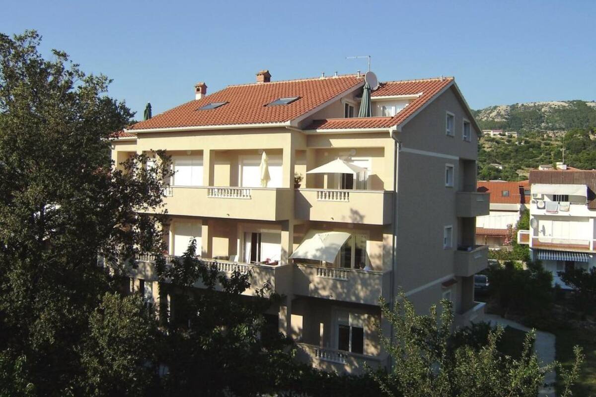 Kerrostalo, jossa on punatiilikatto, parvekkeet ja satelliittiantenni.