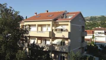 A multi-story residential building with a red-tiled roof, balconies, and a satellite dish.