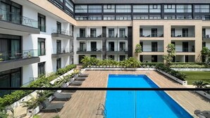A modern building with a rooftop pool, multiple balconies, and lush landscaping. - Opulent 1 Bedroom suite in Embassy Gardens (Accra)