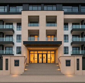 A multi-story hotel with a central entrance, balconies, and a modern architectural design. - Opulent 1 Bedroom suite in Embassy Gardens (Accra)