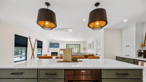 Una cocina moderna con una isla grande, dos lámparas colgantes y una chimenea.