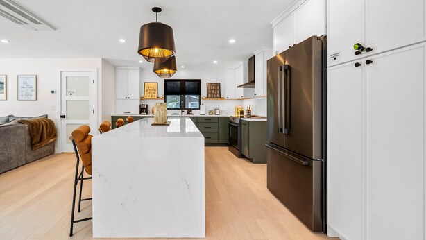 Una cocina moderna con una isla central, electrodomésticos de acero inoxidable e iluminación colgante.