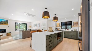 Una cocina moderna con una isla grande, iluminación colgante y horno empotrado.
