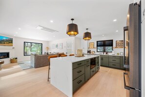 Una cocina moderna con una isla grande, iluminación colgante y horno empotrado.