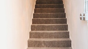 Un escalier menant à un palier où se trouve une source de lumière en haut.