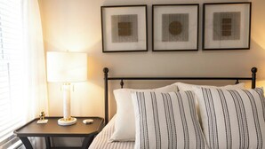 Une chambre d’hôtel bien rangée, avec un lit, une table de chevet dotée d’une lampe et trois œuvres d’art encadrées accrochées au mur.