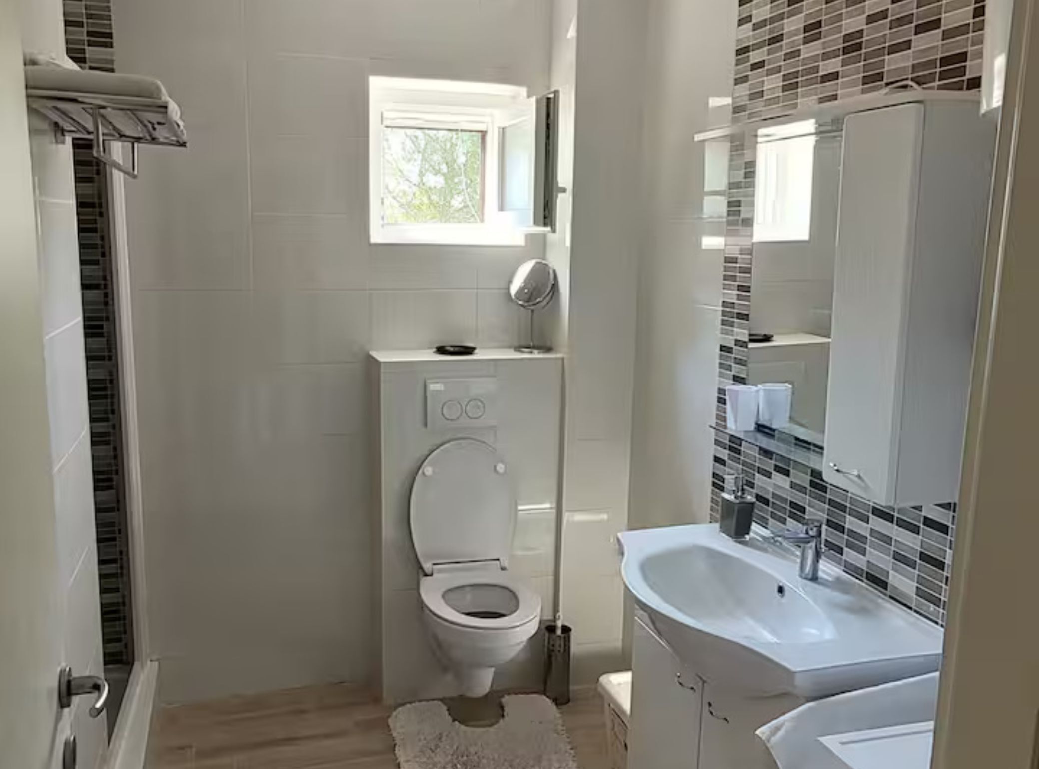 A modern bathroom with a toilet, a small window, a sink, and a mirror.