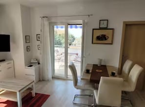 Ein modernes Zimmer mit Bett, Schreibtisch, Stuhl, Tisch und Fernseher.
