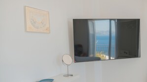 Une pièce avec un téléviseur fixé au mur, un petit miroir rond et un schéma encadré accroché au mur.