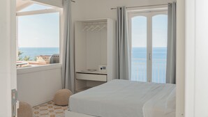 Une chambre avec un lit, un bureau, une armoire et une vue sur la mer.