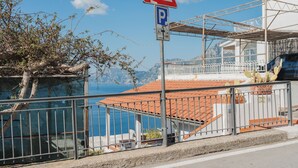 Un bâtiment situé sur la côte, avec un toit recouvert de tuiles rouges, un panneau indiquant un parking et un panneau de passage piéton.