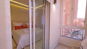 Ein Hotelzimmer mit Bett, einer Schiebetür, einem Fenster und Blick auf die Stadt.