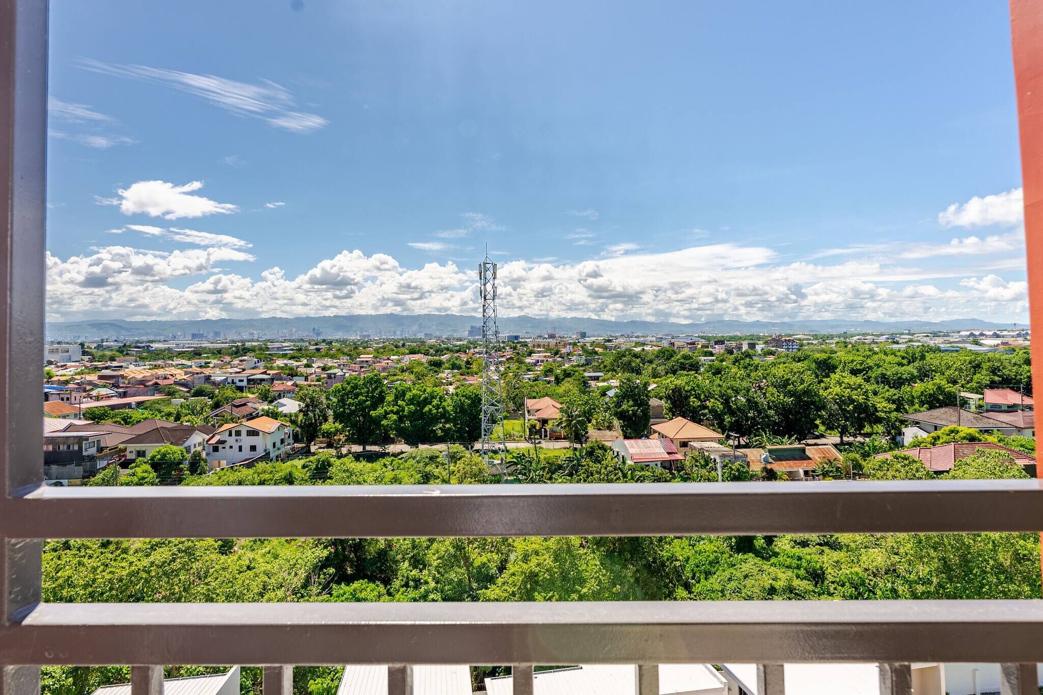 A balcony view of a residential area with houses, trees, and a clear sky.