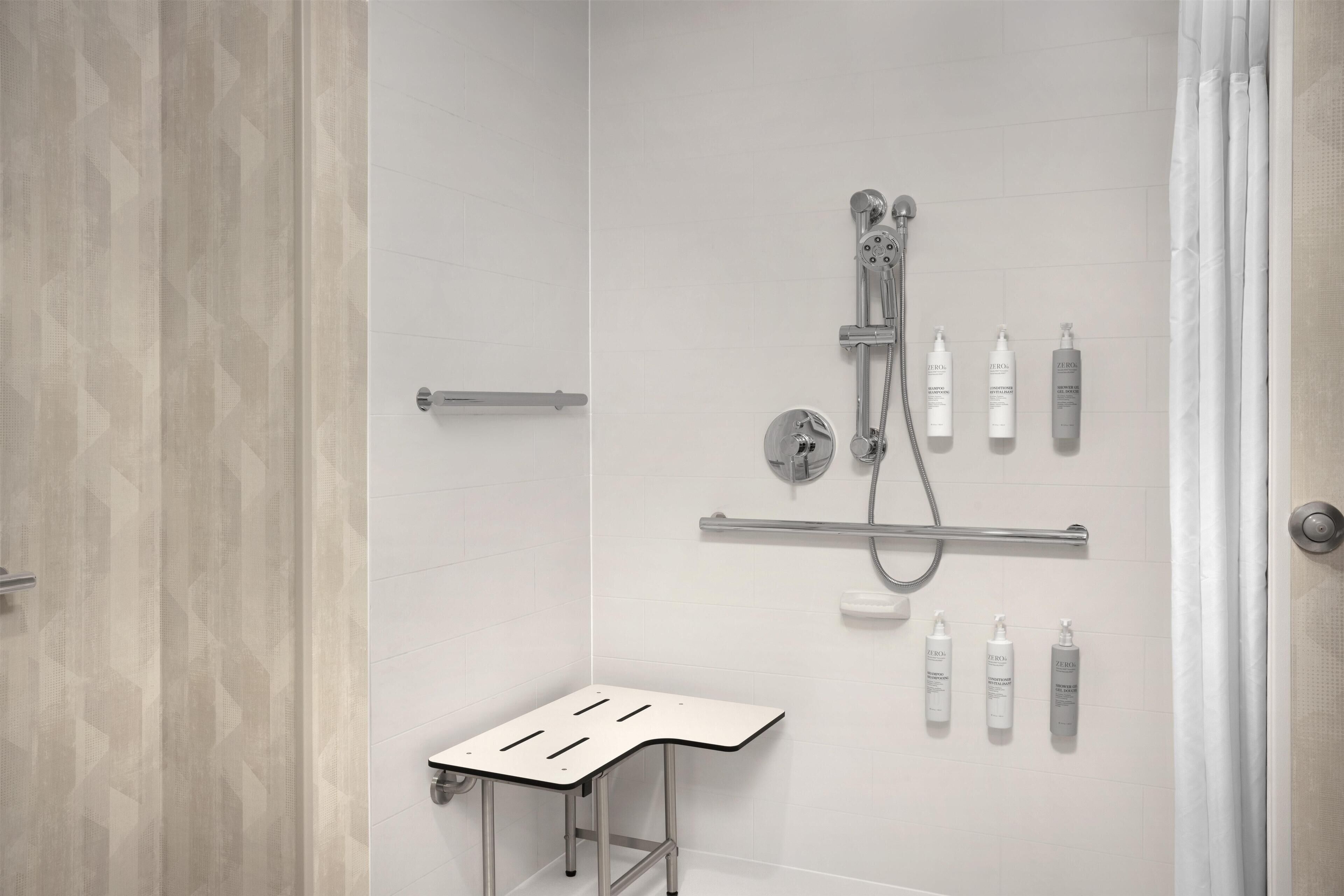 Een moderne douche ruimte met een handdouche, een wandmengkraan en een plank met toiletartikelen.