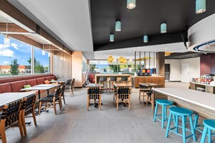 Un interior de restaurante moderno con mesas altas, sillas y una zona de bar.
