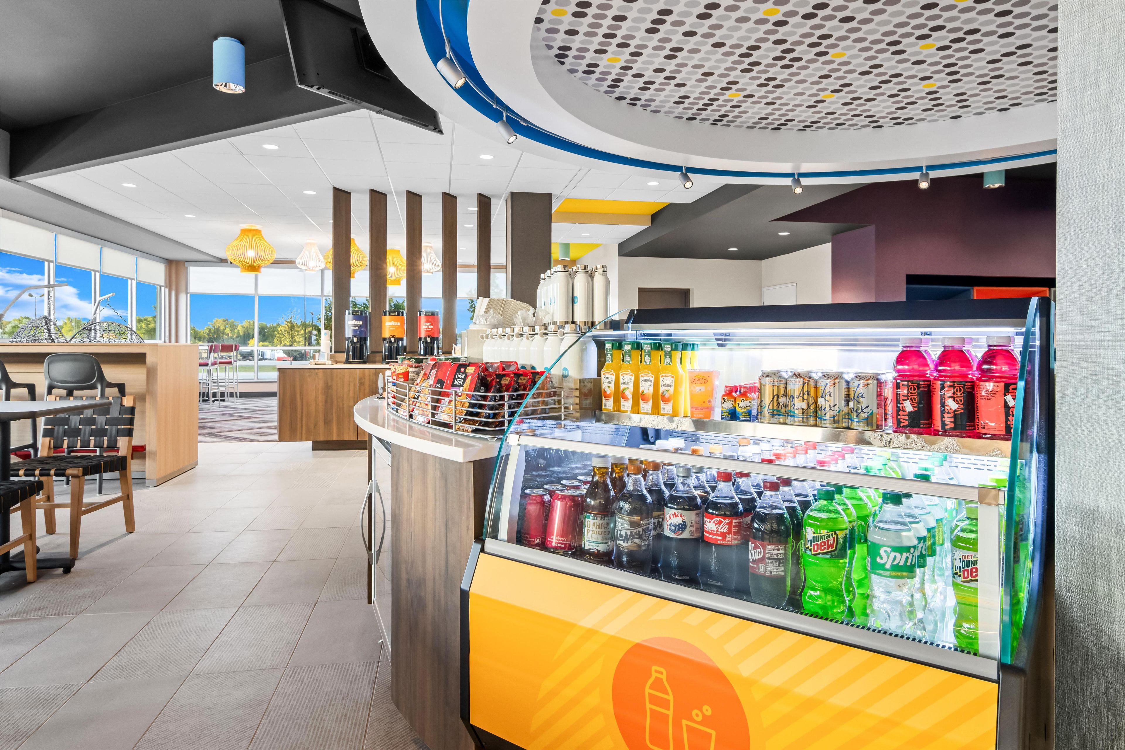 A modern cafe interior with a beverage display, seating area, and large windows.