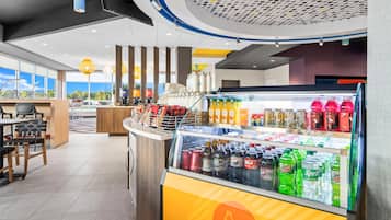 A modern cafe interior with a beverage display, seating area, and large windows.