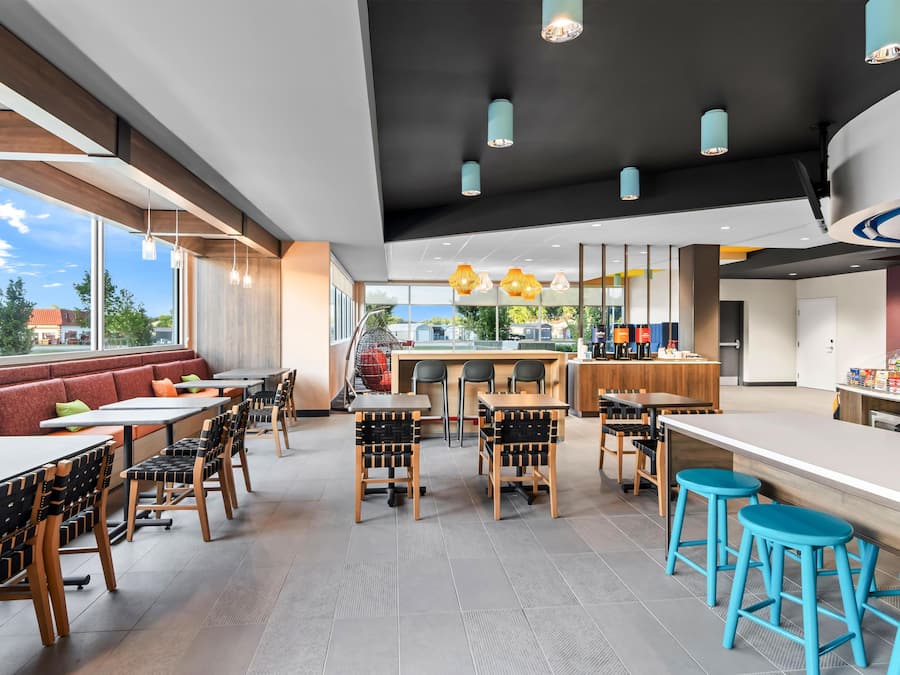 A modern restaurant interior with high tables, chairs, and a bar area.