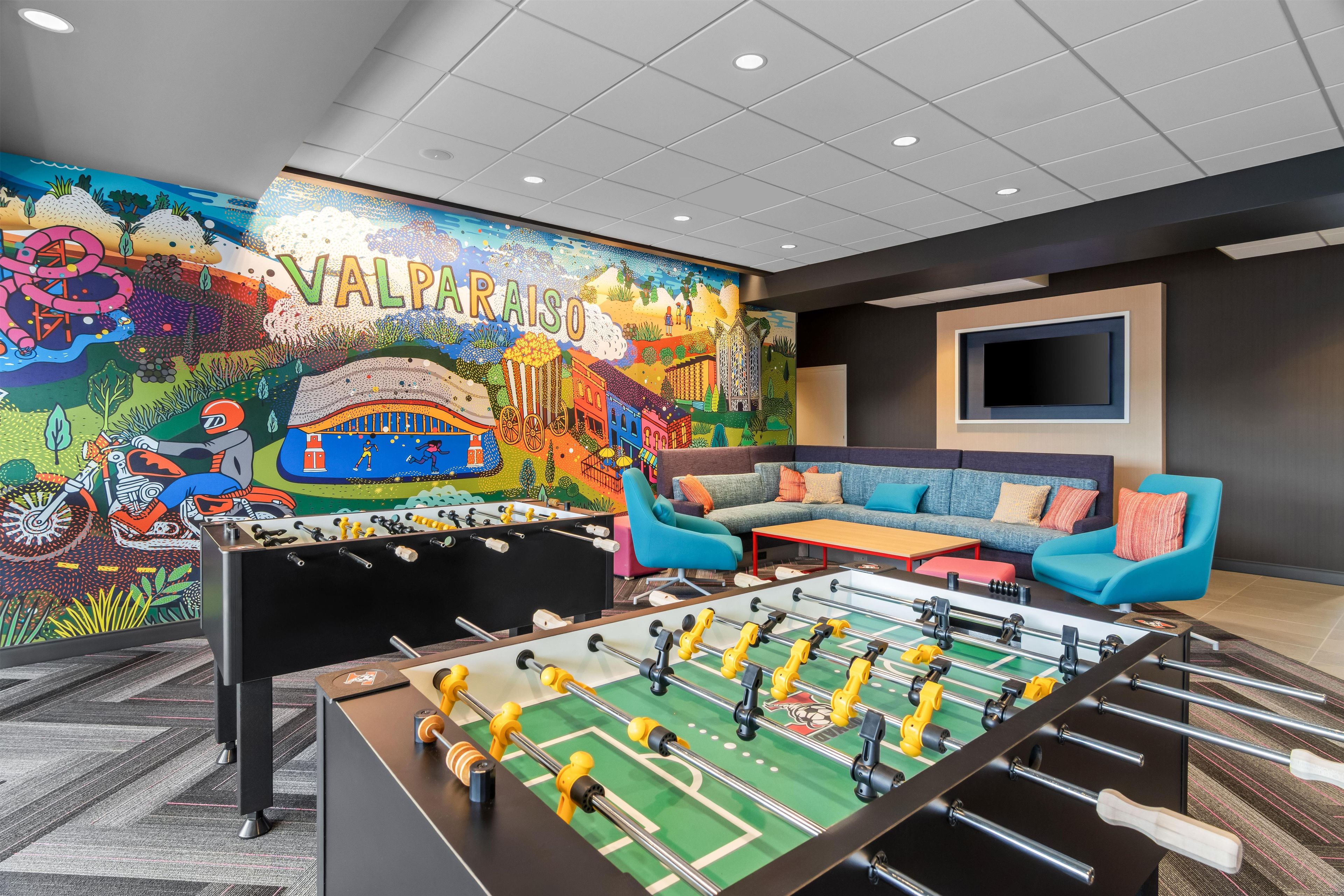 Una habitación con un mural colorido, una mesa de futbolín y un sofá.