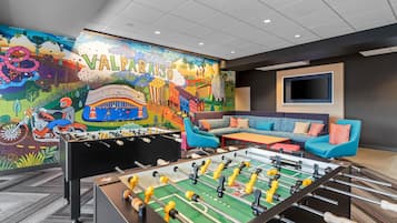 Una habitación con un mural colorido, una mesa de futbolín y un sofá.