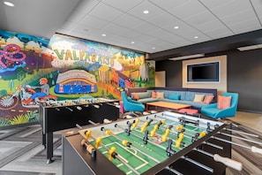 Una habitación con un mural colorido, una mesa de futbolín y un sofá.