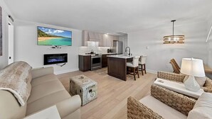 Uma sala de estar moderna com sofá, televisão, cozinha e área de refeições.