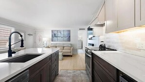 Uma cozinha moderna com armários escuros, uma ilha grande e um espaço de refeições com sofá.