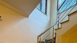 Una escalera con escalones de mármol y barandillas de metal, que lleva a una zona de descanso iluminada con luz amarilla.