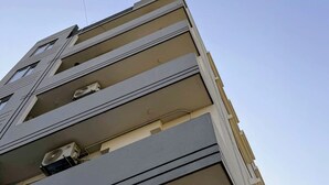A multi-story building with balconies and air conditioning units.