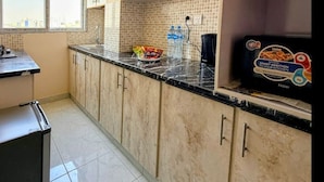 Una cucina con mobili di colore chiaro, zoccolo a mosaico e piano di lavoro nero. Sul piano di lavoro si trova una scatola di elettrodomestici Haier.