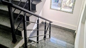 Una scala con ringhiere in metallo nero e gradini in granito che conduce a una piattaforma.