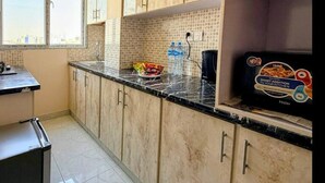 Cucina con mobili chiari, un piano di lavoro nero e una finestra che lascia entrare luce naturale.