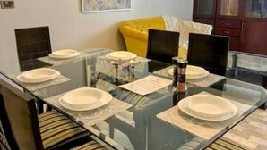 A dining table with six white plates, a glass top, and a menu. - Oceanfront Oasis by Jannat Vacation Rentals (Karachi)