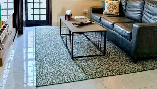 A living room with a sofa, coffee table, and a window with blinds. - Gourmet Getaway One by Jannat Vacation Rentals (Karachi)