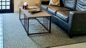 A living room with a leather sofa, a patterned rug, a coffee table, and a lamp. - Gourmet Getaway One by Jannat Vacation Rentals (Karachi)