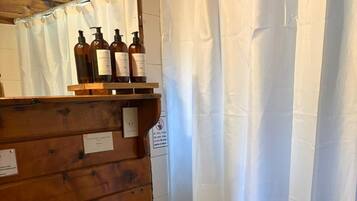 Un bagno con parete in legno, lavandino bianco, un water e una tenda da doccia.